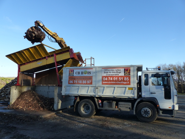 La grue dépose le bois de chauffage dans le camion de livraison