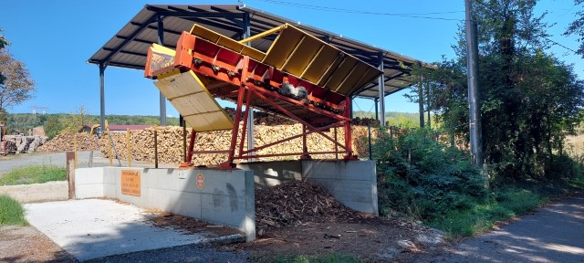 Le cribleur est installé à proximité du hangar de stockage du bois de chauffage